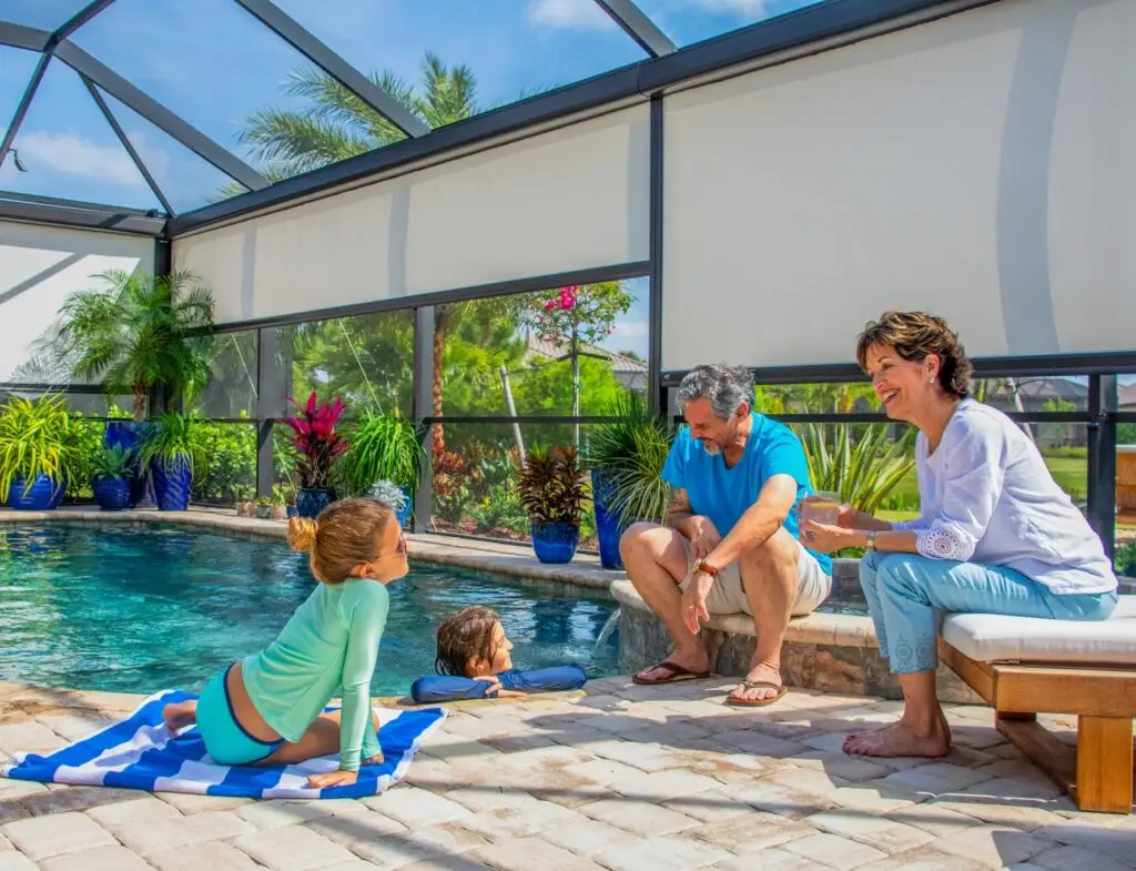 Family relaxing by pool under motorized retractable patio screens